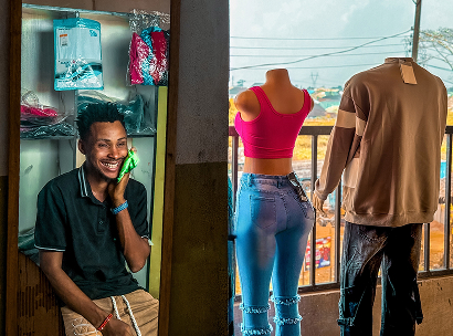 ARRIVES participant, Chris, smiles as he sits in his new fashion business he set up in Nigeria with support from ARRIVES.