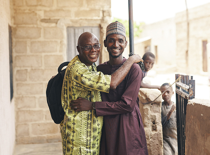 ARRIVES participant, Umar, stands and hugs one of the ARRIVES coaches who helped him start up a solar power business upon returning from Germany to Nigeria.